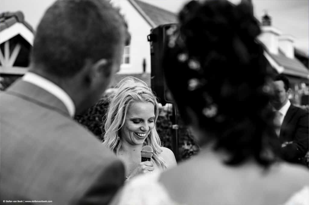 Speech van vrouwelijke bruidsgast gezien tussen het bruidspaar door tijdens bruiloft trouwlocatie de Meerhoeve in Oud Ade © Stefan van Beek Fotografie