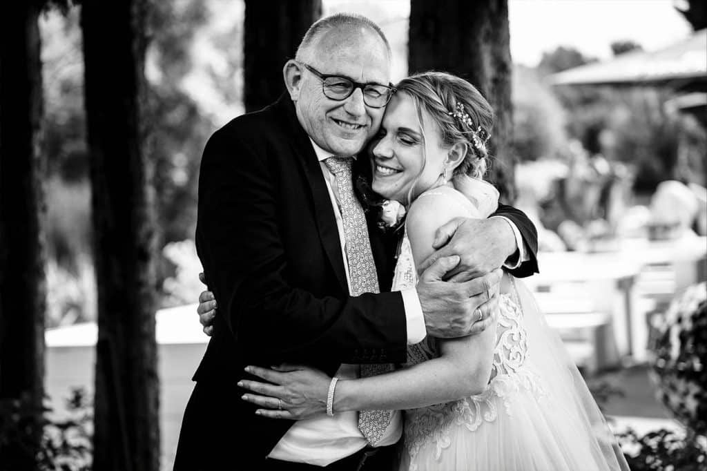 Bruid geeft haar vader een knuffel net voordat hij haar gaat weggeven bij de trouwceremonie © Stefan van Beek Fotografie