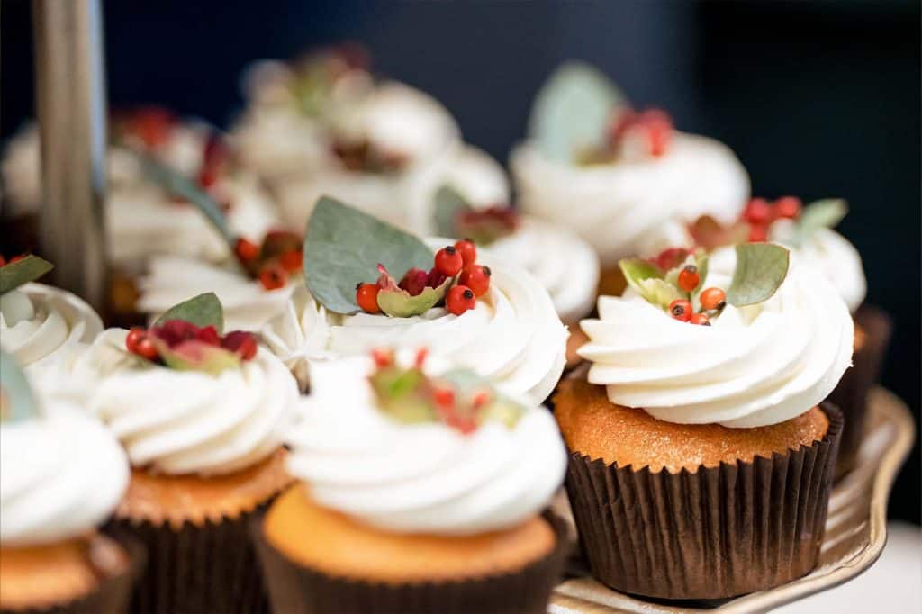 Detail foto van cupcakes in zwart cupcakevormpje met witte slagrooom rode bessen en eucalyptusblad © Stefan van Beek