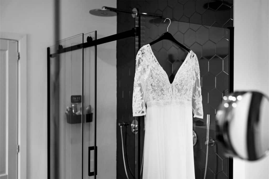 Bruidsjurk hangt aan de glazen douchewand in de badkamer © Stefan van Beek Fotografie