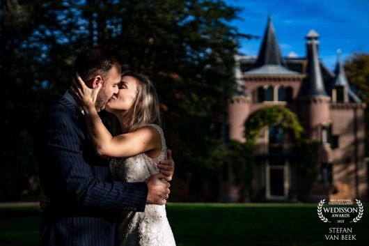 Wedding couple kissing each other in shadow with Castle Keukenhof Lisse on the background Wedisson Award winning photo by wedding photographer Stefan van Beek the Netherlands